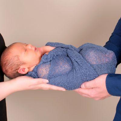L'emmaillotage papa et maman tiennent bébé par la tête et par les pieds emailloté et allongé