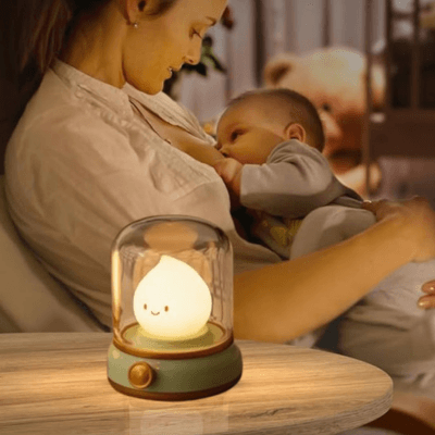 BEBE VEILLEUSE FLAMME - Lanterne Magique™ posée sur une table et éclaire une maman donant le sein à son bebe