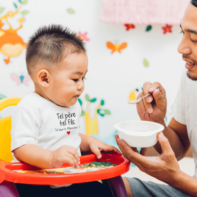 Un père donne à manger à son fil qui porte la Barboteuse Bébé Garçon blanche tel père tel fil