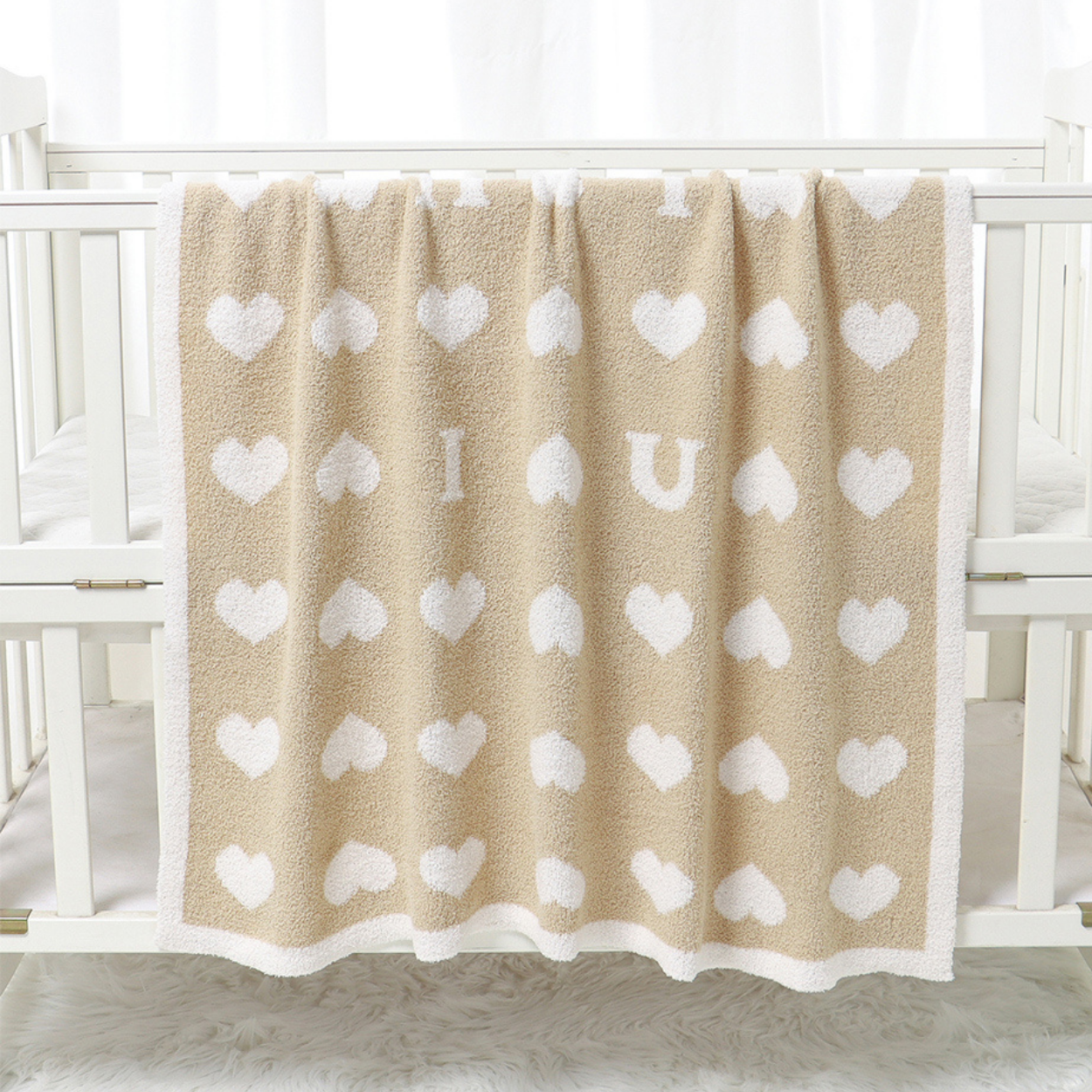 zoom sur la douceur du tissu de la couverture bebe polaire Sérénaya™ couleur sable posée sur le rebord d'un berceau