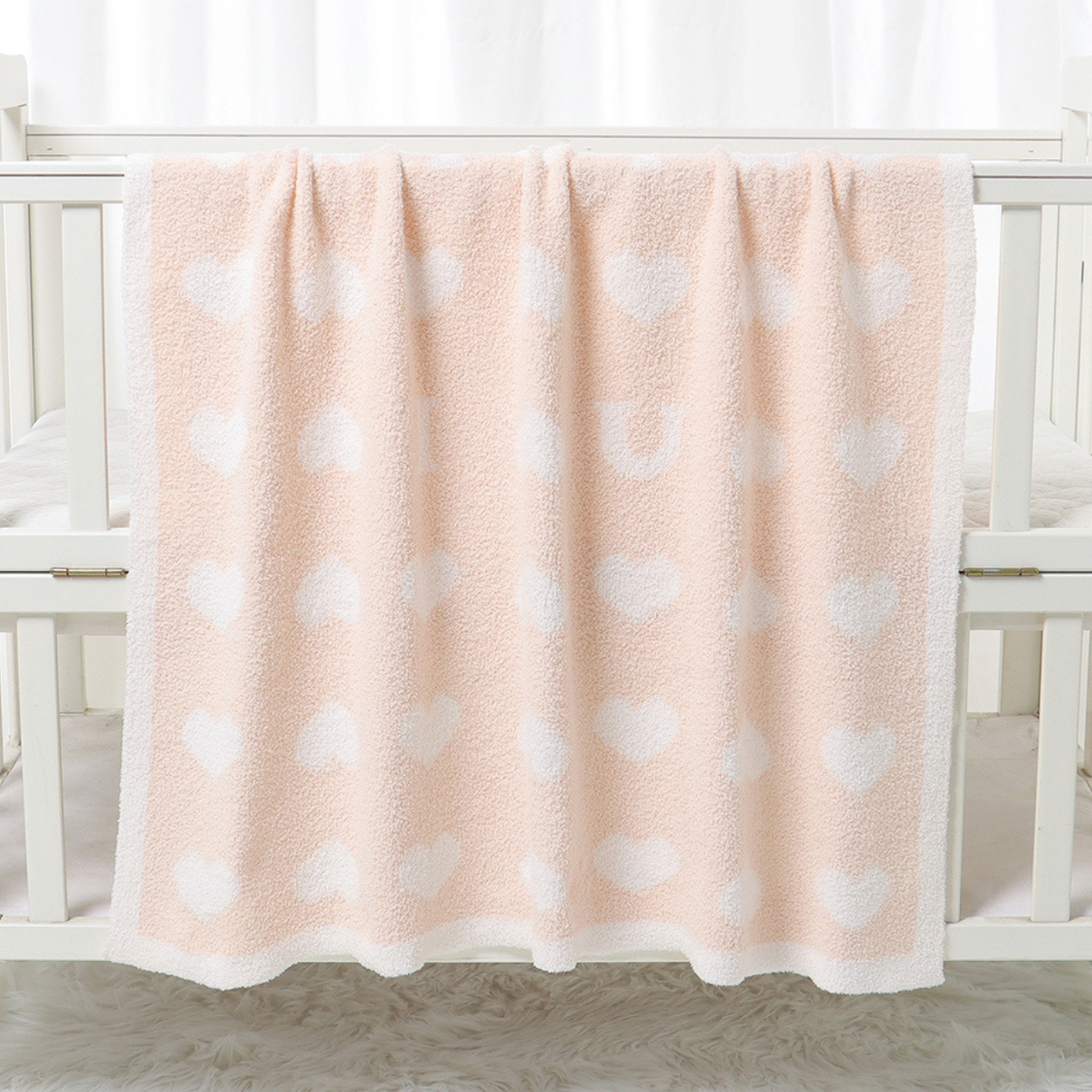 oom sur la douceur du tissu de la couverture bebe polaire Sérénaya™ couleur rose posée sur le rebord d'un berceau