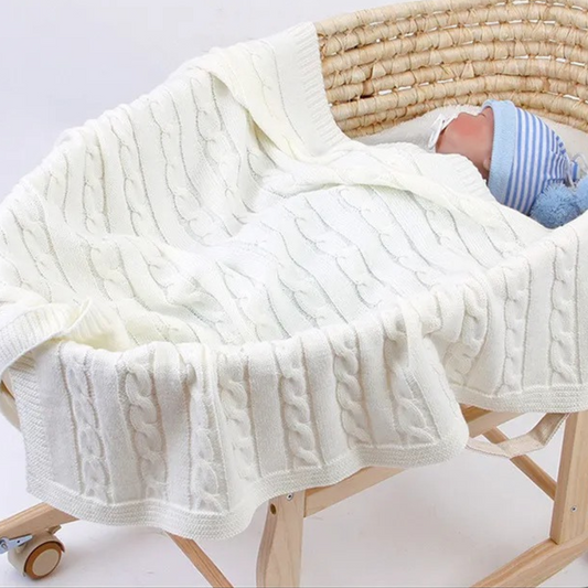 Un bébé dort dans un couffin sur COUVERTURE BEBE TRICOT│Plumy™blanche