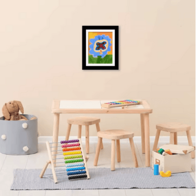Cadre photo en bois noir accroché au mur avec dedans un dessins d'enfant