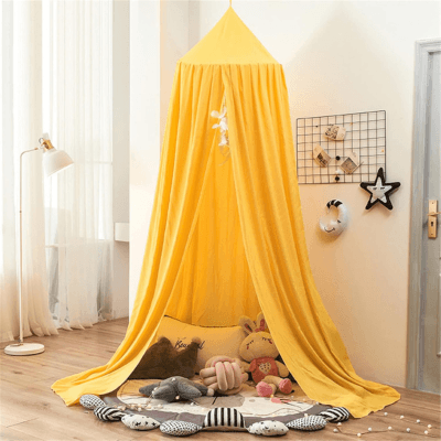 Ciel de lit bébé jaune créant une ambiance cosy et rassurante pour bébé accroché au dessus d'un tapis et de coussins