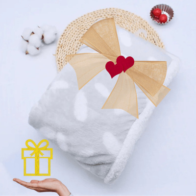 Couverture bébé hiver chaudou grise pliée liée avec un ruban cadeau doré