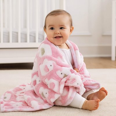 Couverture bebe chaude Calinia™ rose à motifs éléphants, bébé assis souriant enveloppé dans sa couverture douce.