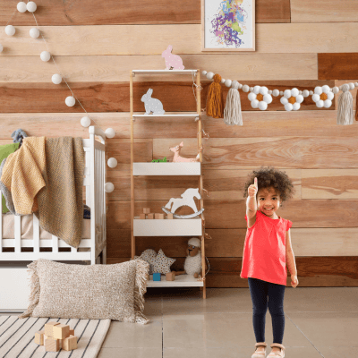 GUIRLANDE - PomponsBoho baby dans une chambre avec une petite fille debout dans la chambre
