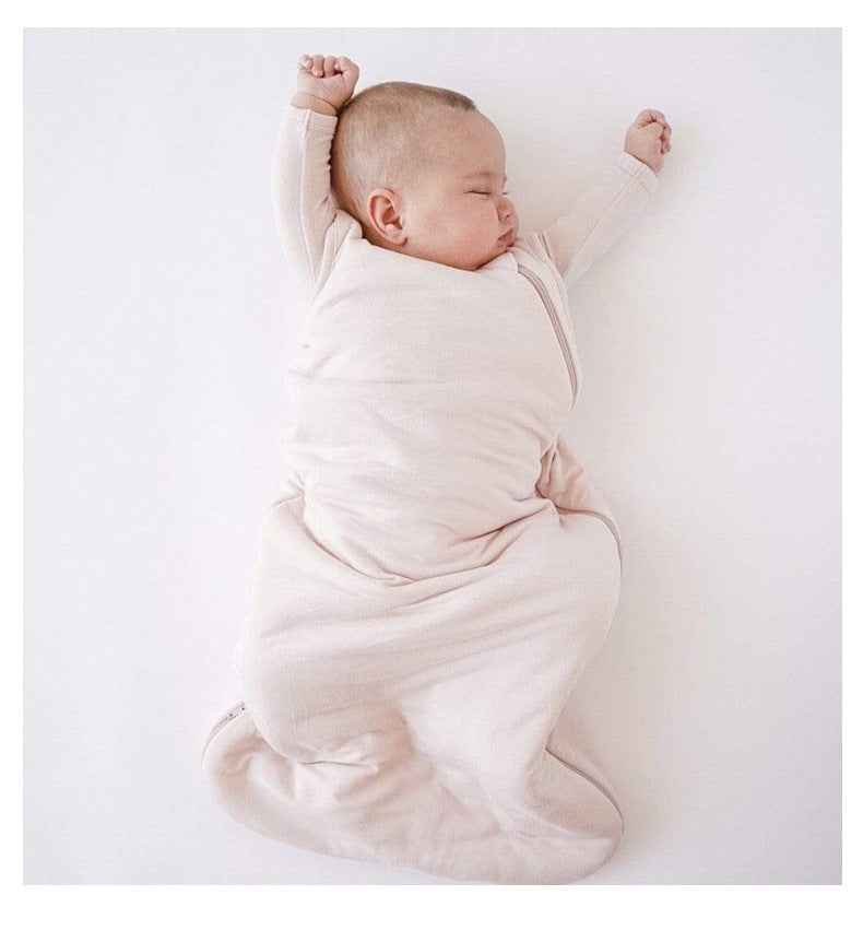 Bébé endormi sur le dos dans une gigoteuse été rose pâle DouxRefuge™, les bras en l’air, paisiblement allongé sur un drap blanc – douceur et liberté de mouvement pendant les nuits chaudes.