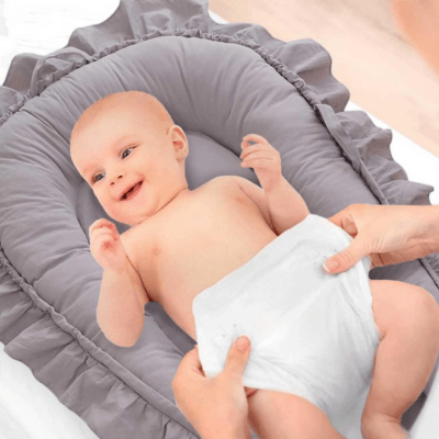 REDUCTEUR DE LIT GRIS - Rêve de Perle™ posé sur une table à langer