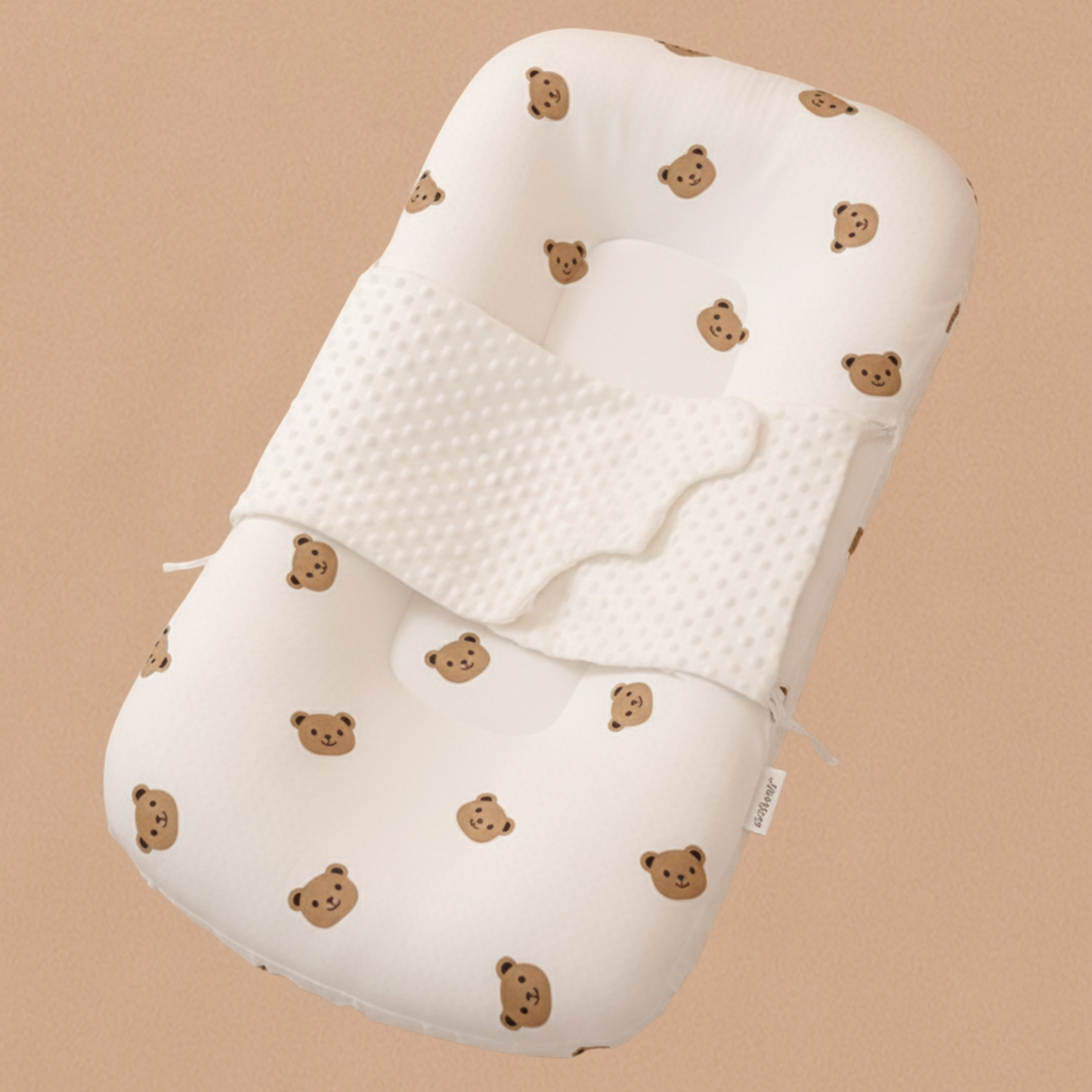 Réducteur de lit beige tête d’ours présenté sans bébé sur un fond caramel