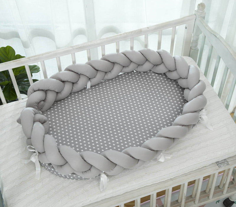 Réducteur de Lit Tressé│Nattou™ gris avec petites étoiles, installé dans un berceau blanc pour chambre de bébé cocooning.