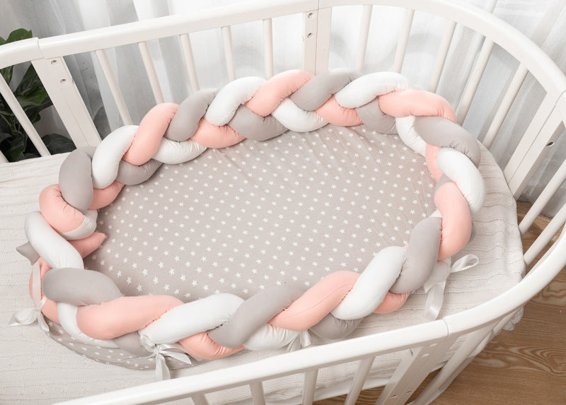 Réducteur de Lit Tressé│Nattou™ rose gris et blanc avec petites étoiles installé dans un berceau blanc pour chambre de bébé cocooning.
