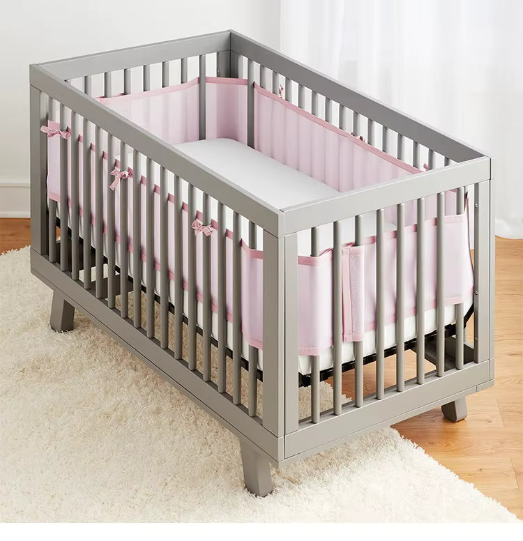 Tour de lit bébé rose PinkyMesh™ installé dans un berceau blanc scandinave, design élégant et respirant, créant une chambre douce et sécurisée.