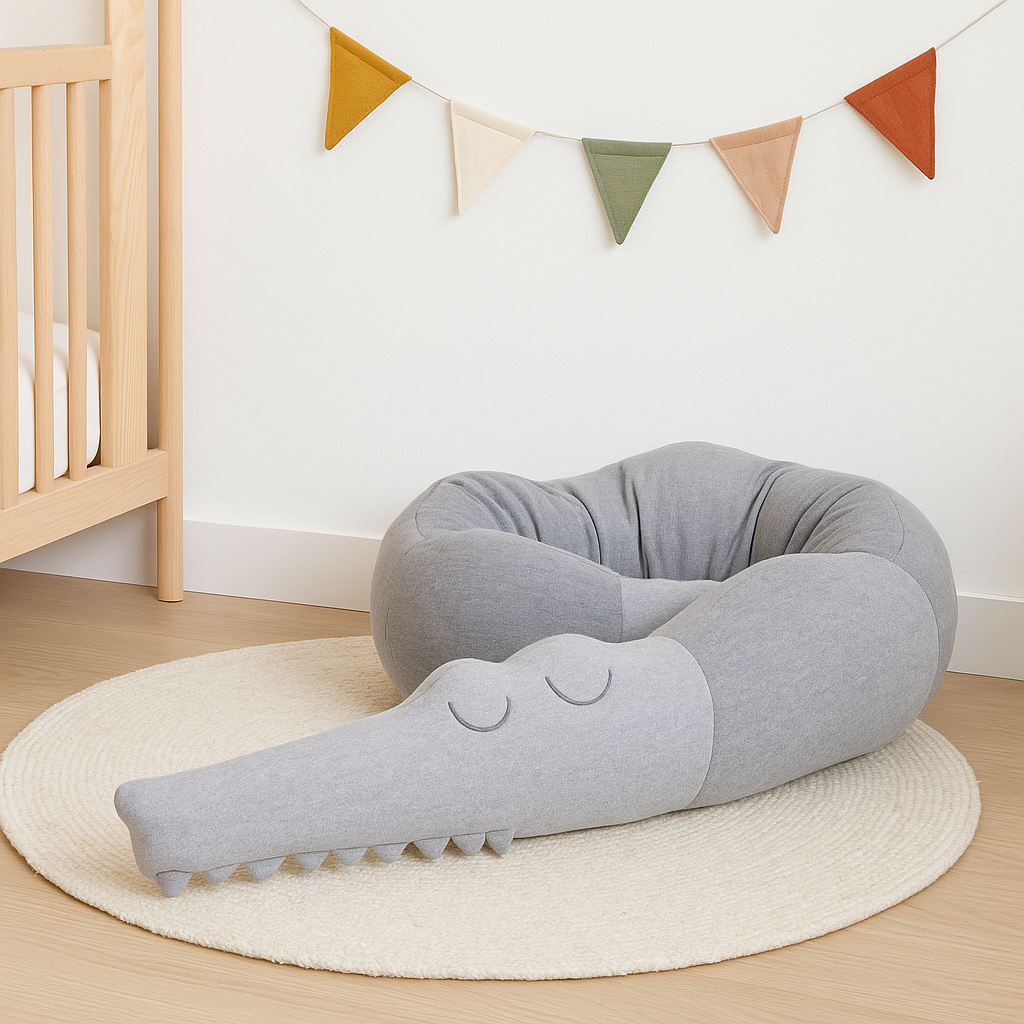Tour de lit bébé gris en forme de crocodile, modèle Crocodile Rêveur™, installé sur tapis rond dans une chambre bébé au style scandinave.