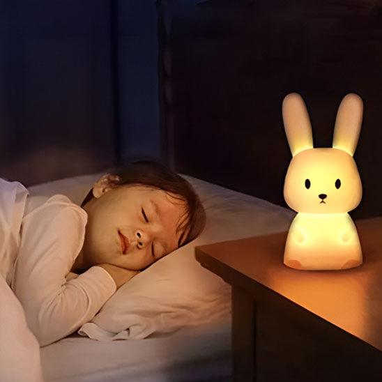 Un petit garçon dort sur le côté gauche une VEILLEUSE BEBE - MonsieurLapinou posée sur sa table de chevet
