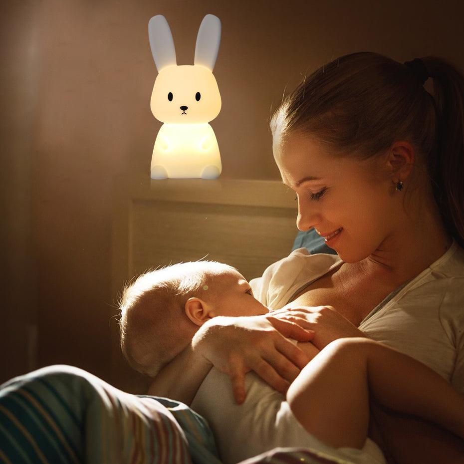 Une maman donne le sein à son bébé la nuit dans la chambre à la lumière d'une VEILLEUSE BEBE - MonsieurLapinou posée sur une commode