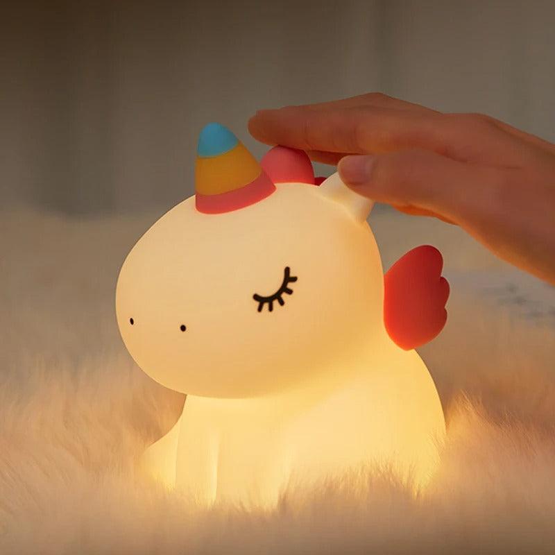 Une main tapote sur la tête de la VEILLEUSE BEBE LICORNE - MissUnicorn™pour l'allumer