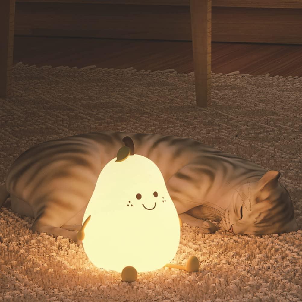 Un chat dort sur un tapis une VEILLEUSE BEBE POIRE posée à côté de lui