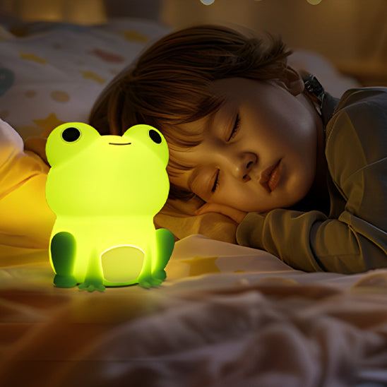 Enfant endormi avec une veilleuse grenouille bébé allumée posée sur le lit