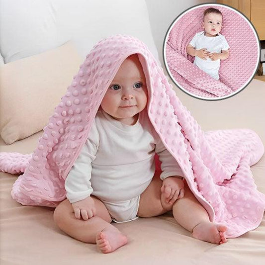 Bébé assi au sol avec une couverture-en-polaire-bebe-confort sur la tête