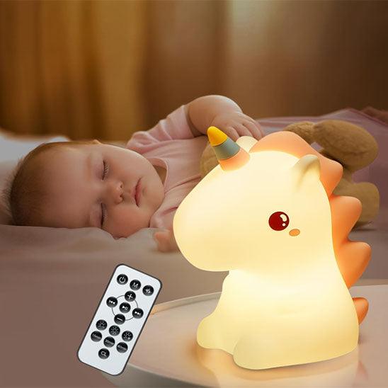 Un bébé dort avec une VEILLEUSE BEBE - Mademoiselle Licorne allumée sur la table de chevet et sa télécommande en gros plan