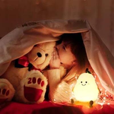 Petite fille sous une couverture avec sa peluche éclairée par une VEILLEUSE BEBE - MademoisellePoire