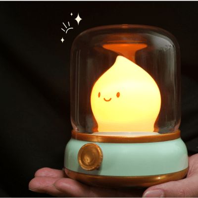 BEBE VEILLEUSE FLAMME - Lanterne Magique™ - Vert posée dans une main éclaire d'une lumière jaune