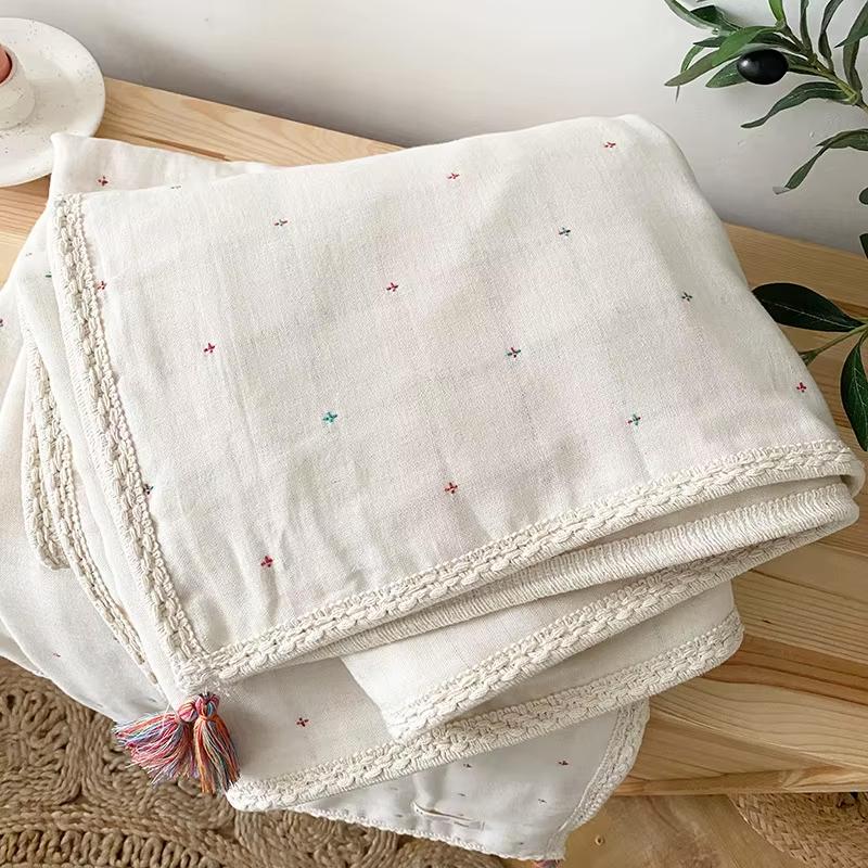 Gros plan sur la COUVERTURE_BEBE_EN_COTON_BIOLOGIQUE_NaturaDouce_-_Croix_de_boheme posée sur un meuble