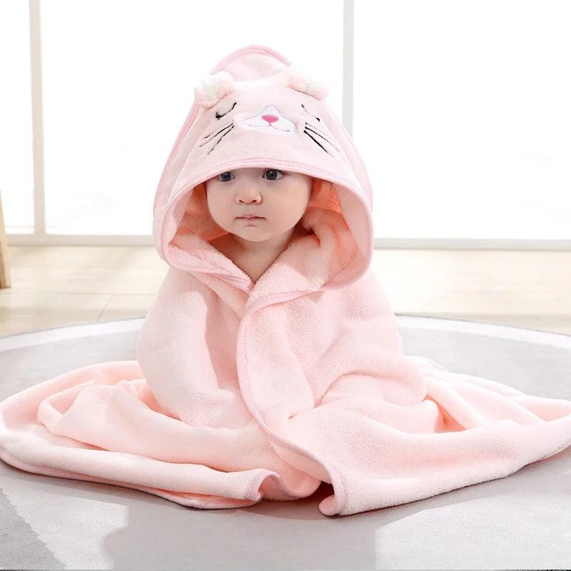 Un bebe assis au sol porte le Cape de Bain Bébé - Douceur Câline™ Rose-Chat avec la capuche sur la tête