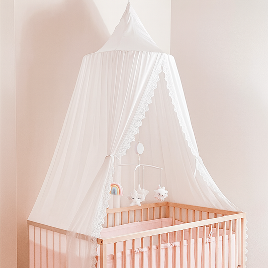Ciel de Lit Bébé Blanc Névélia™ installé au-dessus d’un lit bébé en bois clair avec décoration rose, créant une ambiance douce et rassurante.