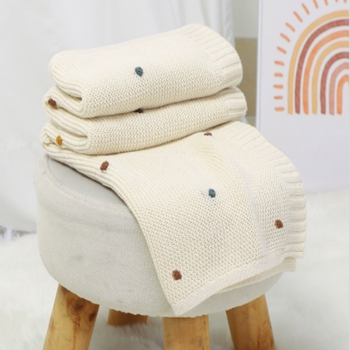 Gros plan sur la Couverture Bébé Tricot Coton│DouceMaille™ - Blanc posée sur un tabouret