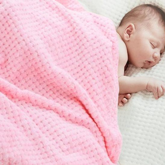 Un bébé dort recouvert d'une Couverture Bébé en Minky Polaire - LandaCâlin™ Rose