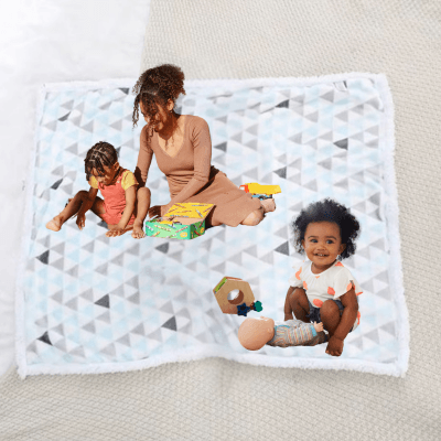 Une maman assise au sol avec ses deux filles jouent sur une couverture bébé chaudou