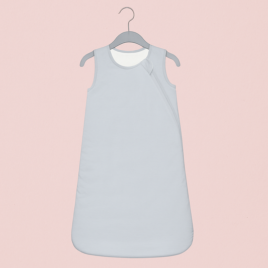 Gigoteuse Printemps et Automne gris clair accrochée à un cintre gris, sur fond rose poudré élégant, style épuré et moderne.