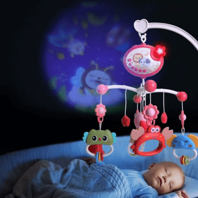 Un bébé dort paisiblement dans une chambre sombre pendant que le Mobile Bébé Musical et Lumineux -  StellaTune™ projette des image sur le mur de la chambre