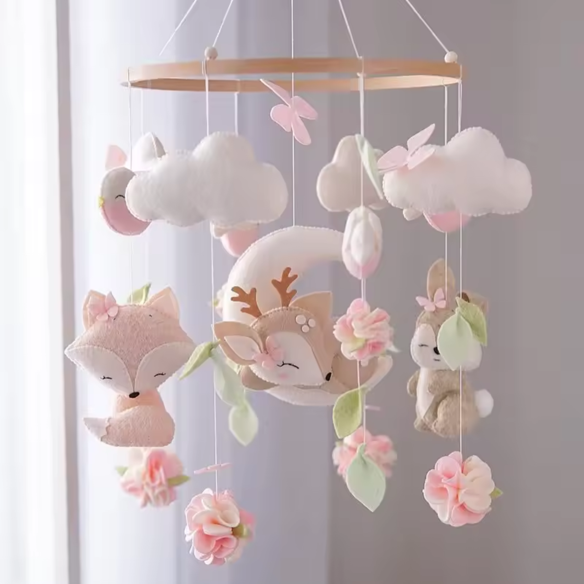 mobile bébé en feutrine rose avec animaux suspendus dans une chambre douce et lumineuse