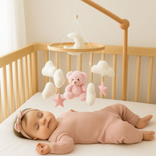 Mobile lit bébé ours rose Rosalia™ au-dessus d’un bébé endormi paisiblement dans son berceau.