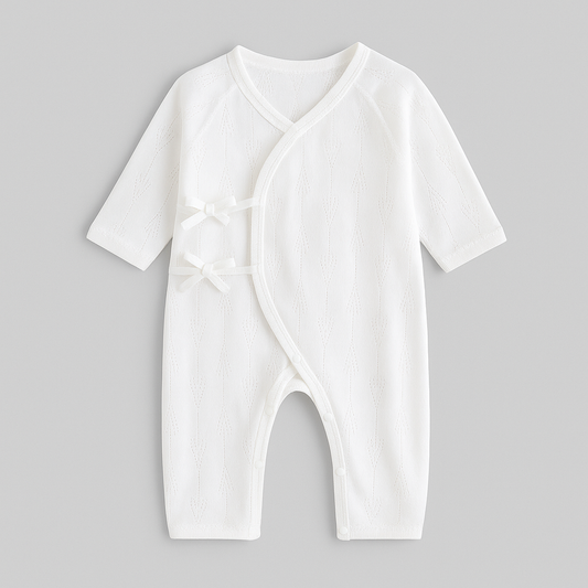 Pyjama bebe en coton blanc uni mi-saison avec petits nœuds latéraux et tissu respirant, conçu pour le confort et le sommeil serein des nouveau-nés.