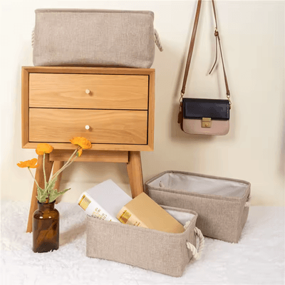 Panier de Rangement Pour Bébé beige posée sur une table de chevet deux autre modèles de la meme couleur posés au sol