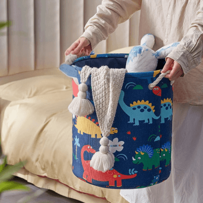 Femme portant un panier Panier de Rangement pour Bébé - Terre des Dinos™ en tenant par les deux anses en corde avec doudou et jouet à l'inétieur 