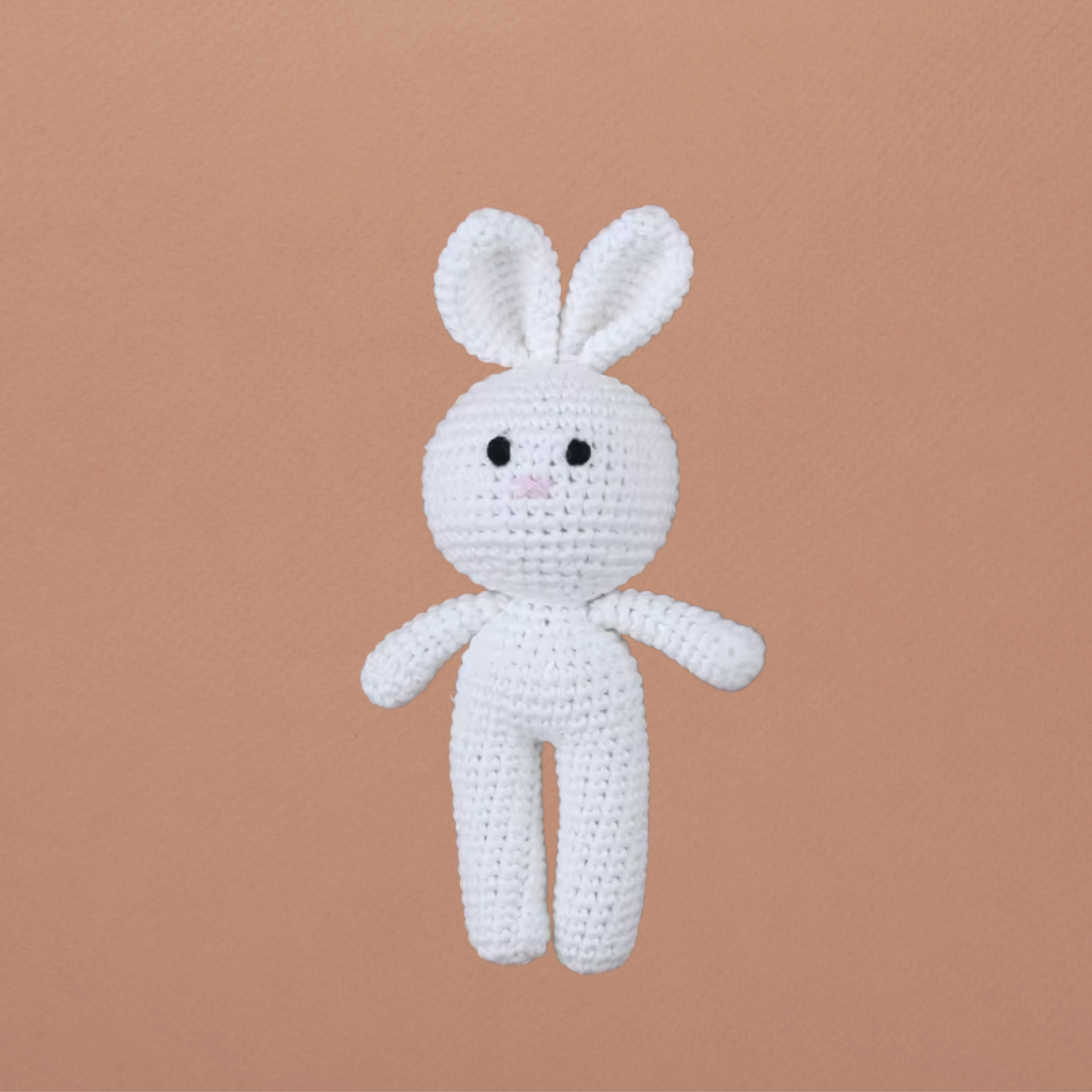Petit doudou lapin blanc Calimail™ 15 cm, en coton crocheté sur fond terracotta clair.