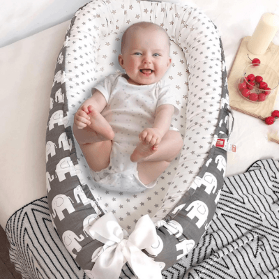 Bébé installé dans un REDUCTEUR DE LIT- Cocon Rêveur™, en sécurité et entouré de douceur.