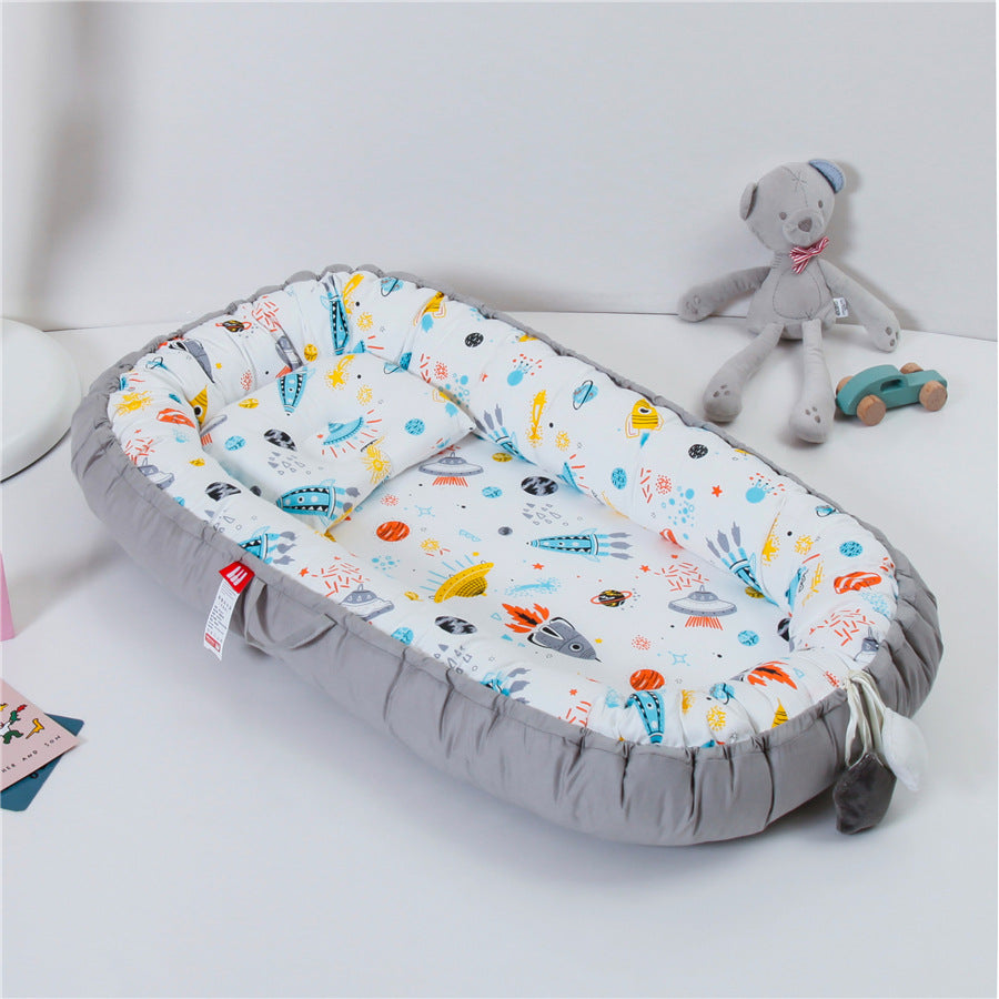 REDUCTEUR DE LIT POUR BEBE 100% COTON Sodalite™ motifs fusées et planètes, ambiance ludique avec peluche et jouet en arrière-plan.