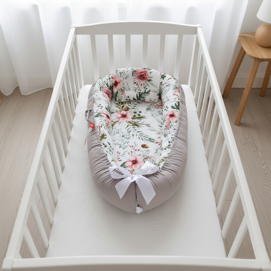 Reducteur_de_lit_bebe_fleuri_rose_et_gris_installe_dans_un_berceau_blanc_offrant_un_cocon_securisant_et_confortable_pour_le_sommeil_de_bebe