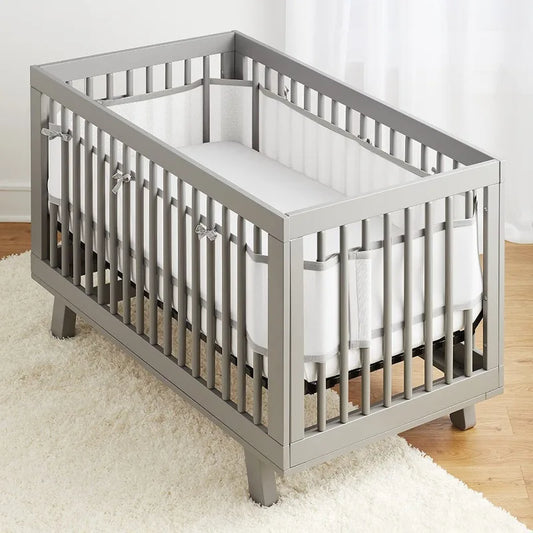 Berceau gris équipé du tour de lit respirant gris et blanc Meshidoux™, installé derrière les barreaux pour une sécurité optimale et un design élégant.
