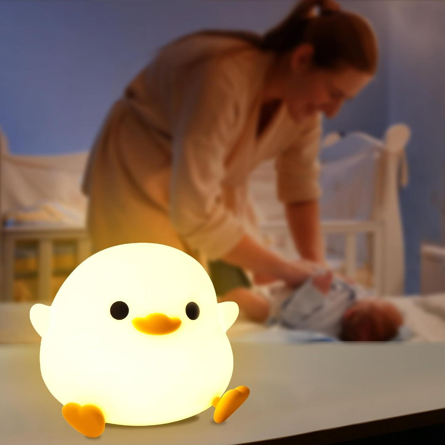 Une maman change son bébé dans la chambre la nuit à la lumière d'une VEILLEUSE BEBE CANETON