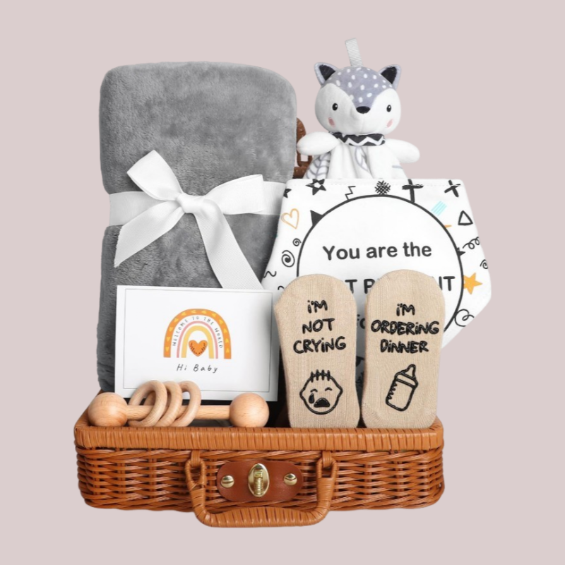 Coffret naissance bebe gris WelcomeBaby comprenant couverture moelleuse, doudou renard et chaussettes fun dans un panier en osier.