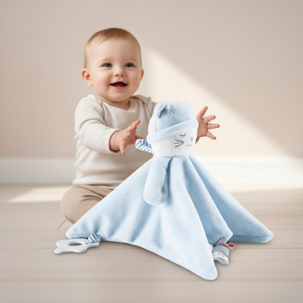 Bébé assis jouant avec le doudou bébé PlushyDream™ bleu, debout devant lui avec anneau de dentition blanc et étiquettes sensorielles, dans une ambiance douce et lumineuse.