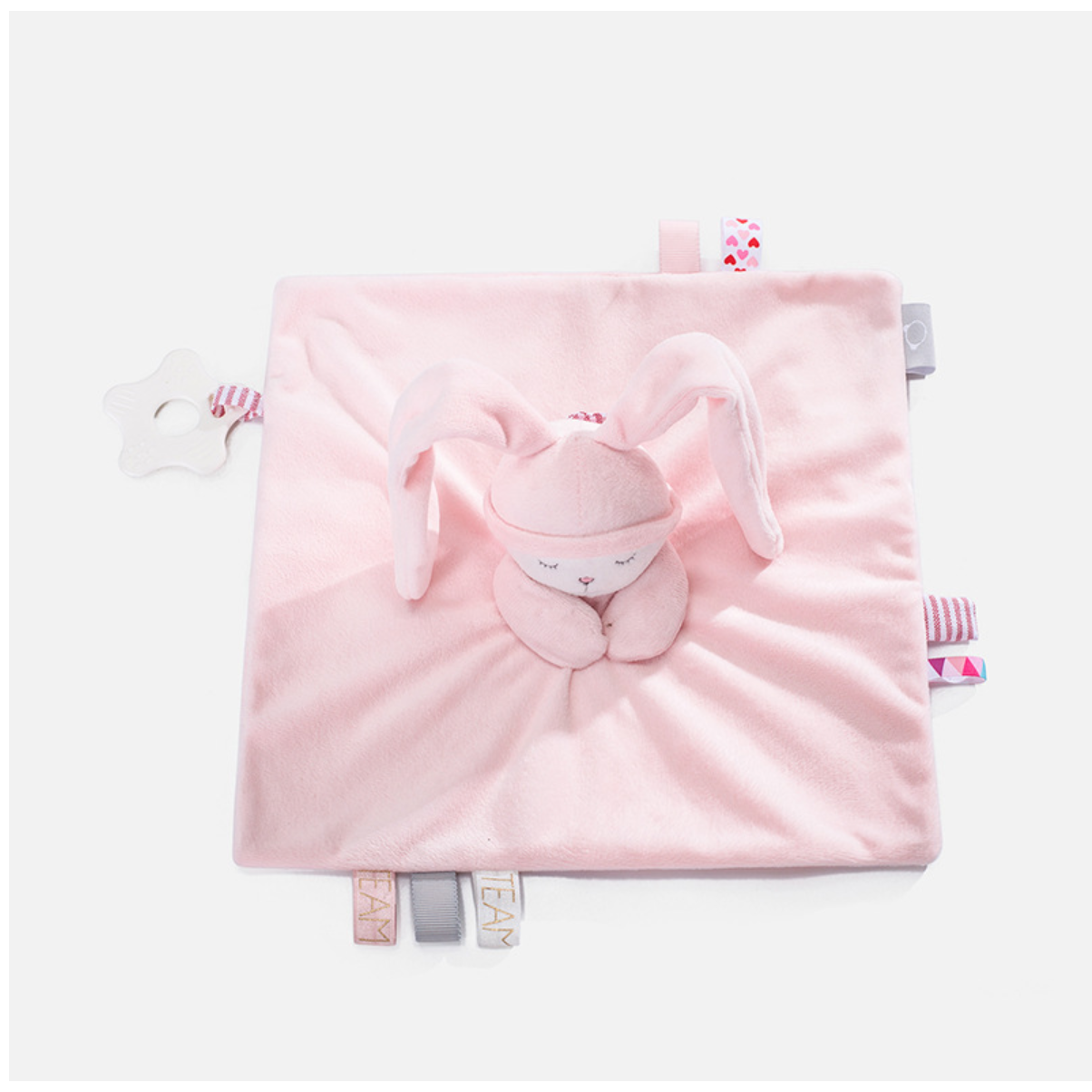 Doudou bébé PlushyDream™ rose en carré plat avec tête brodée, grandes oreilles souples, étiquettes sensorielles et anneau de dentition blanc, présenté sur fond clair.