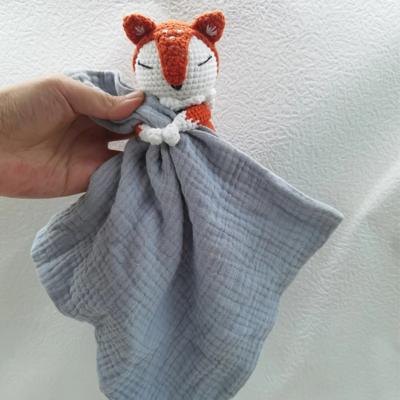 Doudou bébé renard FoxyRoux gris bleu en gaze de coton avec tête crochetée, tenu en main